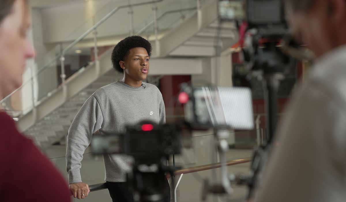Student standing in front of a camera being interviewed for an educational or nonprofit video production.