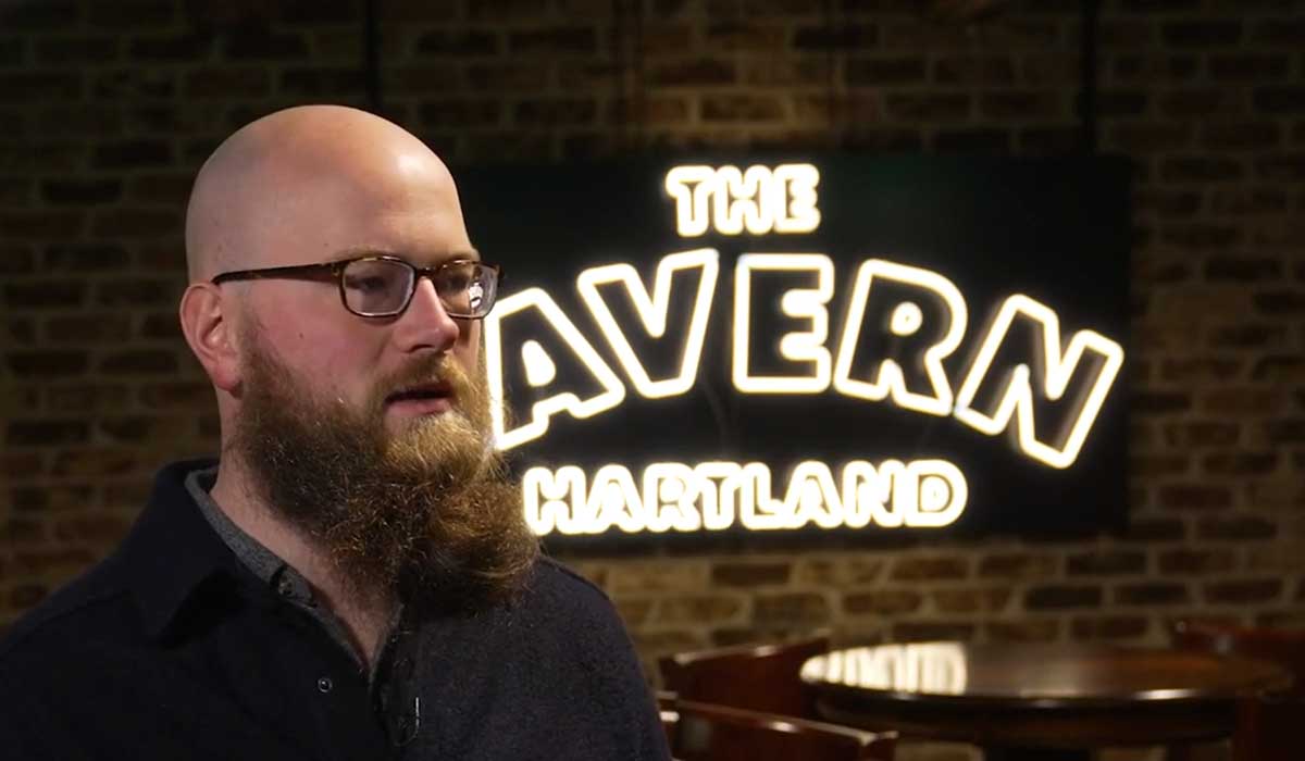 Anthony Deutsch seated for an interview in front of The Cavern sign at BlueSky Jazz in Hartland, Wisconsin.