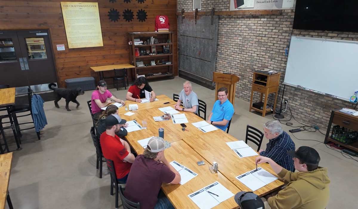 Students seated with mentors around the conference table inside the CWC conference room at Edgerton Gear’s manufacturing plant.