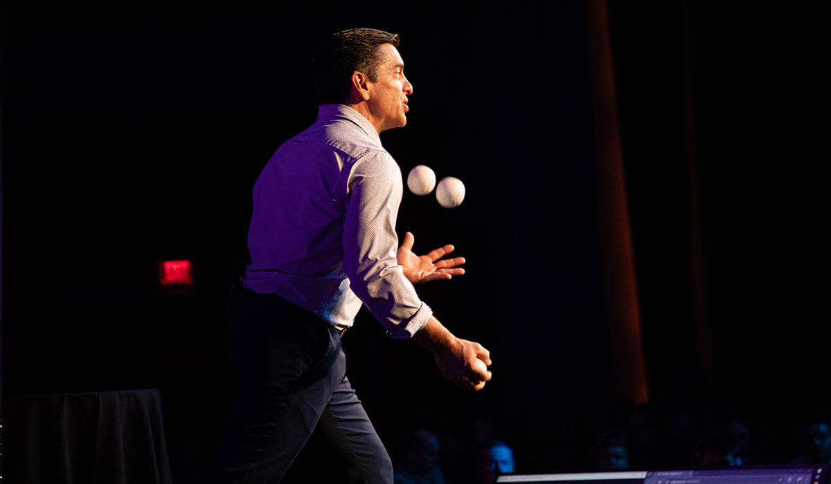 Juggling Keynote – Converge Tech Summit Keynote speaker juggling three objects mid-performance during a high-energy presentation at the Converge Technology Summit in Milwaukee