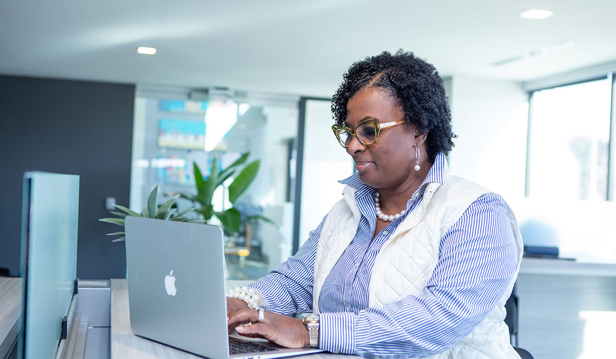 Woman Leader Deep in Focus on Her Laptop Focused woman leader working intently on her laptop in a modern office setting