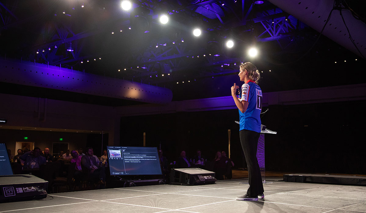 Side view of Leah Pruitt delivering a keynote address on stage at a tech summit