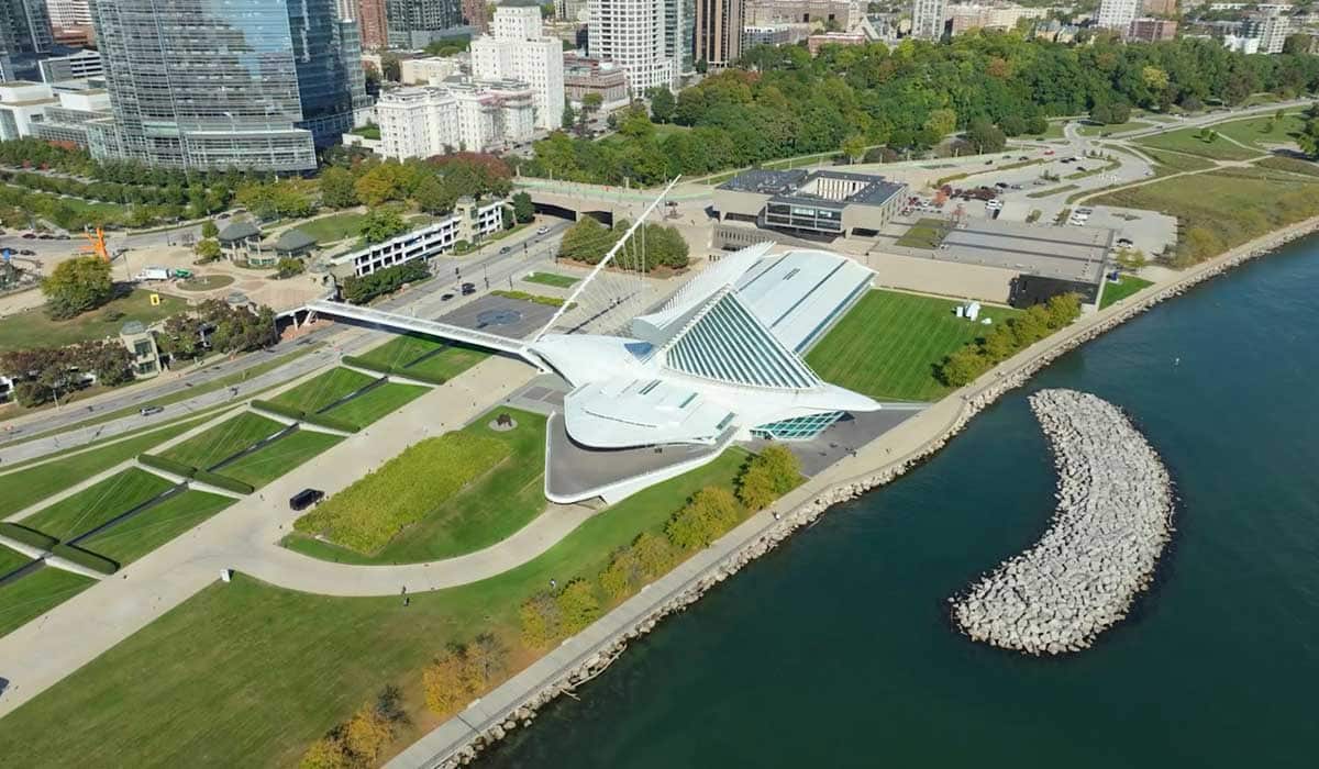 Distant drone shot of the Milwaukee Art Museum’s Calatrava wing, captured over Lake Michigan with the Milwaukee skyline in view